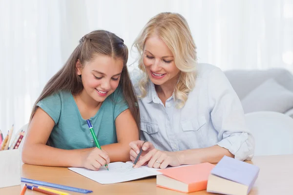 Smiling mother helping daughter with homework Royalty Free Stock Photos