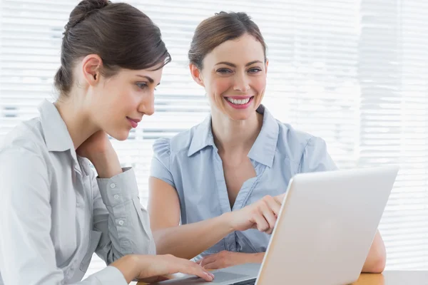 Duas empresárias sorridentes trabalhando no laptop juntas — Fotografia de Stock