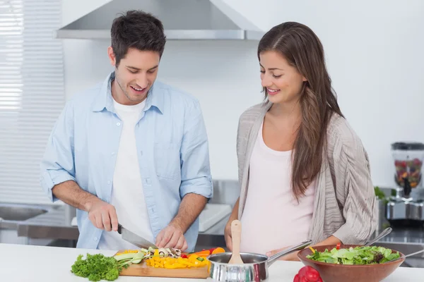 Uomo tagliando funghi accanto alla sua partner incinta — Foto Stock