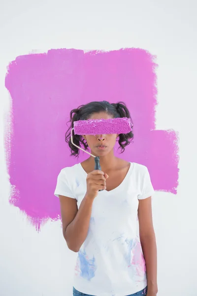 Happy woman holding paintroller over her face — Stock Photo, Image