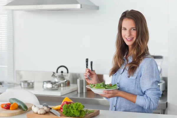 Woman in the kitchen holding a salad bowl with lettuce — Stock Photo, Image