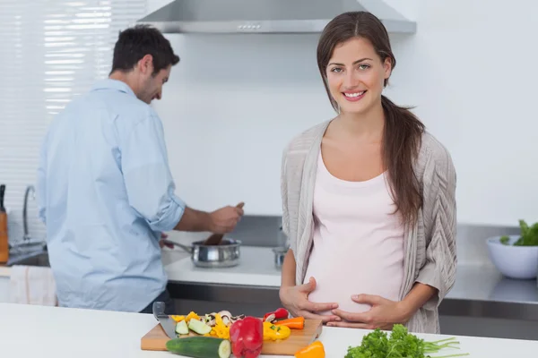 Pregnant woman holding her belly in the kitchen — Stock Photo, Image