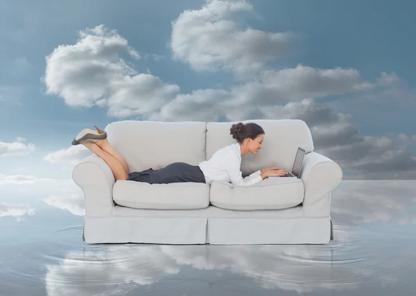 Бизнесмен лежит на диване и печатает на ноутбуке — стоковое фото