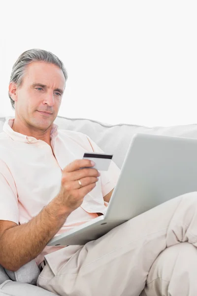 Man op zijn bank met behulp van laptop voor online winkelen — Stockfoto