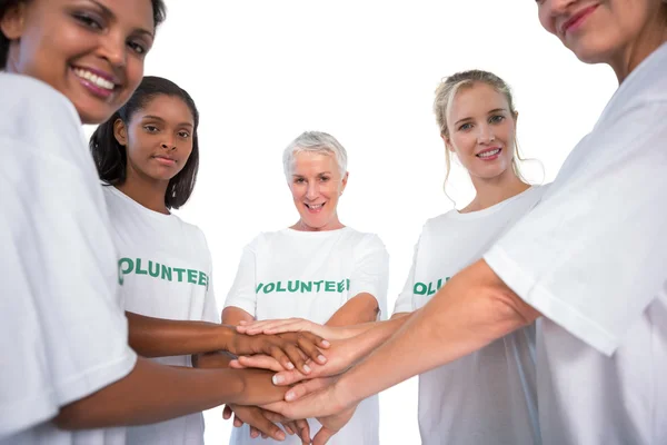 Team of female volunteers with hands together smiling at camera — Stock Photo, Image