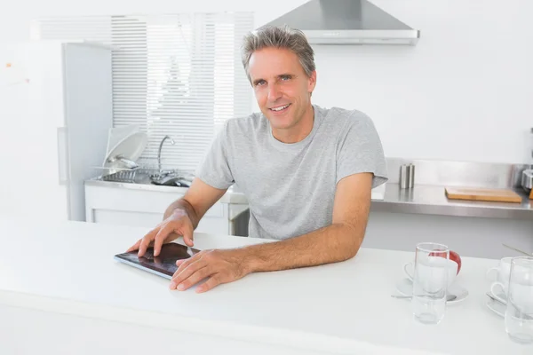 Hombre feliz usando la tableta PC en la cocina —  Fotos de Stock