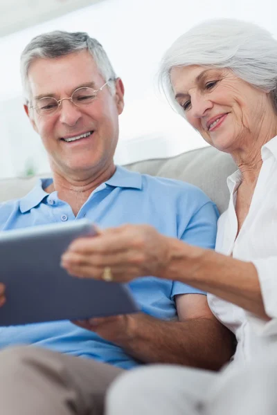 Casal usando um tablet digital sentado no sofá — Fotografia de Stock