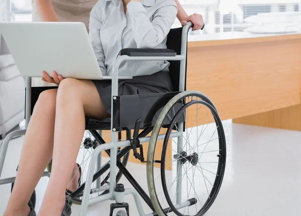 Disabled businesswoman showing laptop to colleague — Stock Photo, Image