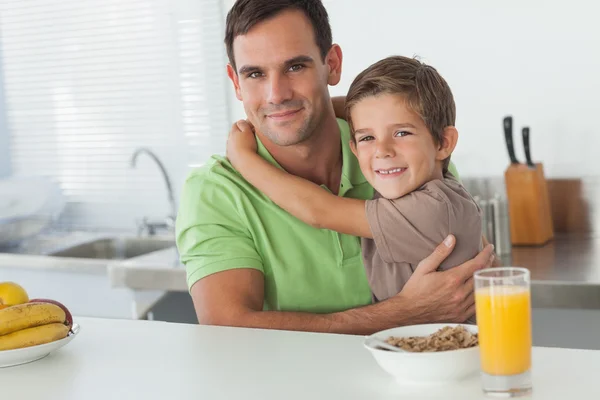 Figlio che abbraccia suo padre mentre fa colazione — Foto Stock