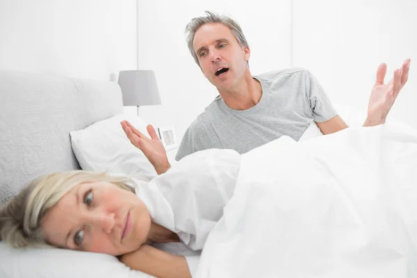 Homme plaidant avec son partenaire contrarié au lit — Photo