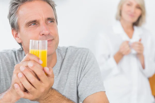 Glimlachende man drinken sinaasappelsap in keuken — Stockfoto