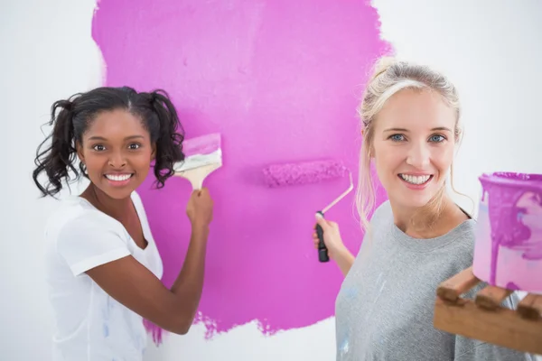 Alegre jóvenes compañeros de casa pintura pared rosa — Foto de Stock