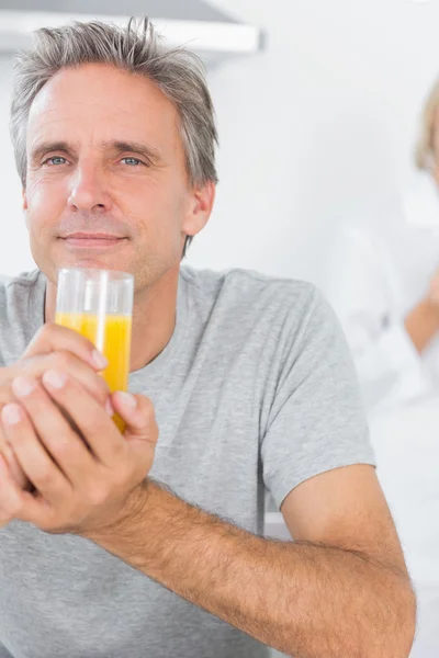 Hombre alegre bebiendo jugo de naranja en la cocina — Foto de Stock