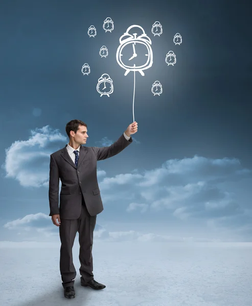 Businessman holding a floating alarm clocks — Stock Photo, Image