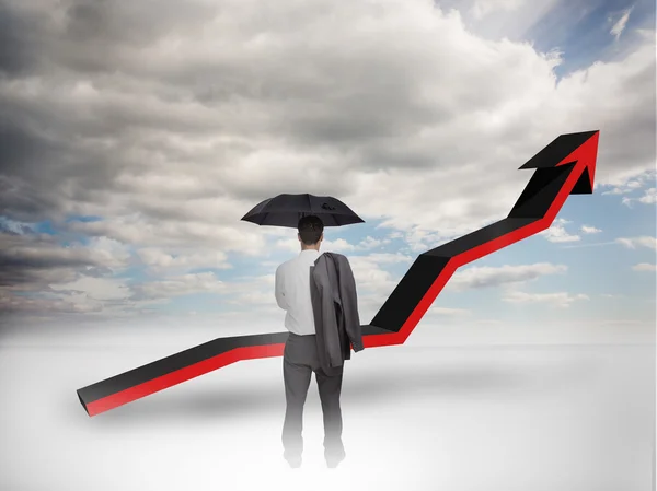 Businessman under an umbrella looking at a red arrow — Stock Photo, Image