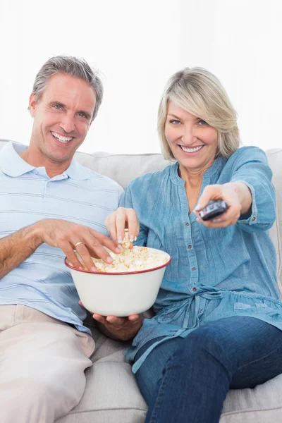 Paret tittar på tv och äta popcorn i soffan — Stockfoto