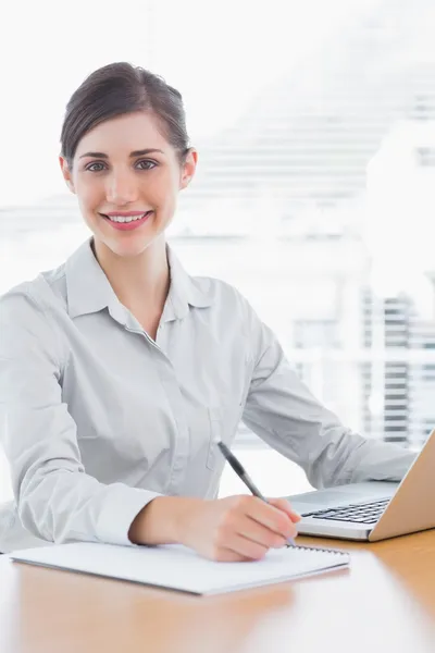 Bastante mujer de negocios trabajando y sonriendo a la cámara —  Fotos de Stock