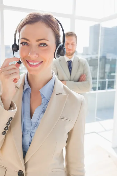 Call centre agent smiling with colleague behind her — Stock Photo, Image