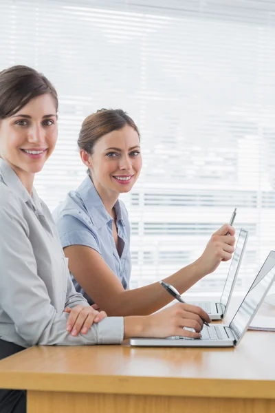 Glimlachen van vrouwelijke ondernemers werken op hun laptops portret — Stockfoto
