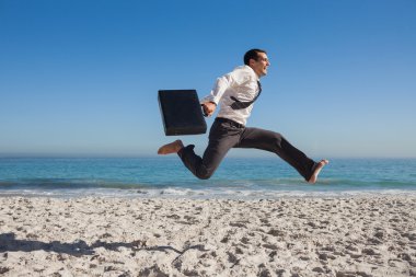 Cheerful businessman jumping on the beach clipart