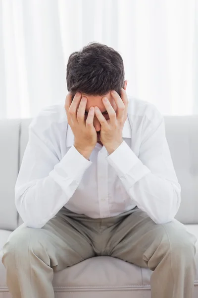 Unhappy young man sitting on sofa — Stock Photo, Image