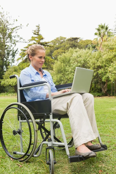 快乐的女人坐在轮椅上使用的便携式计算机 — 图库照片