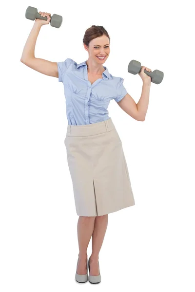 Strong businesswoman lifting dumbbells looking at camera — Stock Photo, Image