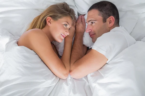 Bonito casal deitado e olhando um para o outro na cama — Fotografia de Stock
