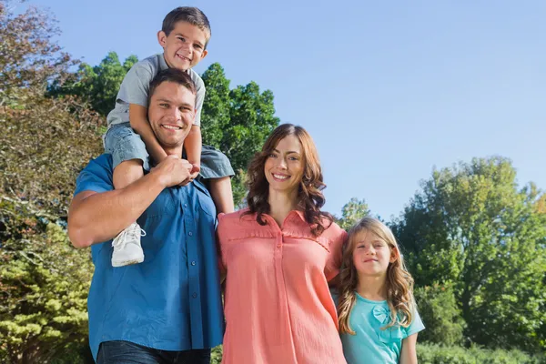 Glückliche Familie lächelt im Park in die Kamera — Stockfoto