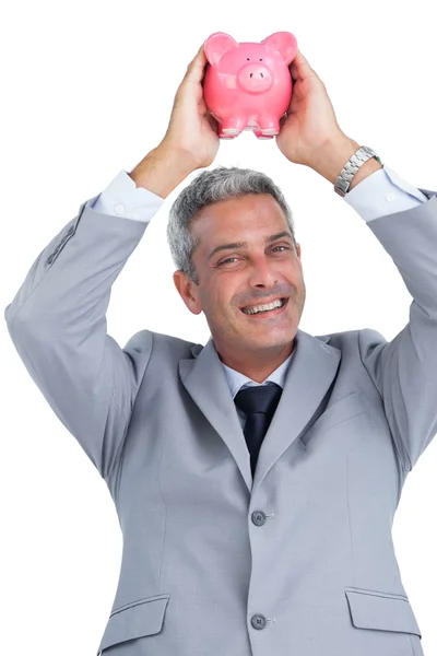 Cheerful businessman holding piggy bank above his head — Stock Photo, Image