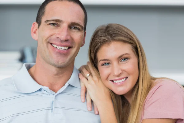 Feliz casal sentado no sofá sorrindo para a câmera — Fotografia de Stock