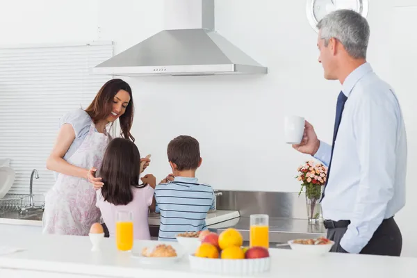 Отец смотрит на свою семью, готовящую на кухне. — стоковое фото