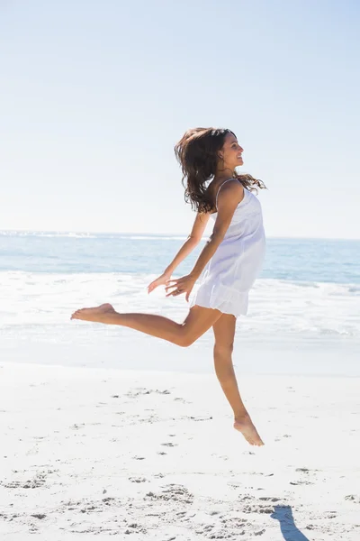 Morena feliz em vestido de sol branco dançando na areia — Fotografia de Stock