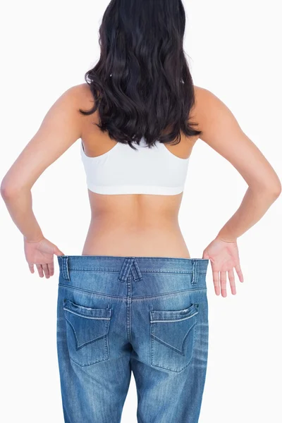 Terug holding van vrouw haar te groot jeans — Stockfoto