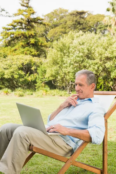 Uomo che utilizza il computer portatile sul lettino — Foto Stock