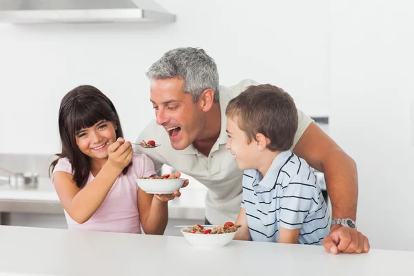 Menina dando cereal para seu pai com o irmão sorrindo — Fotografia de Stock