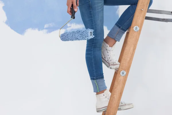 Mujer sosteniendo rodillo de pintura en escalera — Foto de Stock