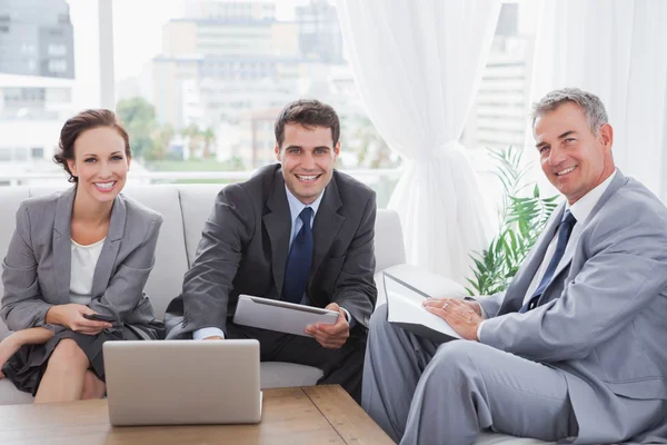 Mensen uit het bedrijfsleven glimlachen in de camera terwijl het hebben van een vergadering — Stockfoto