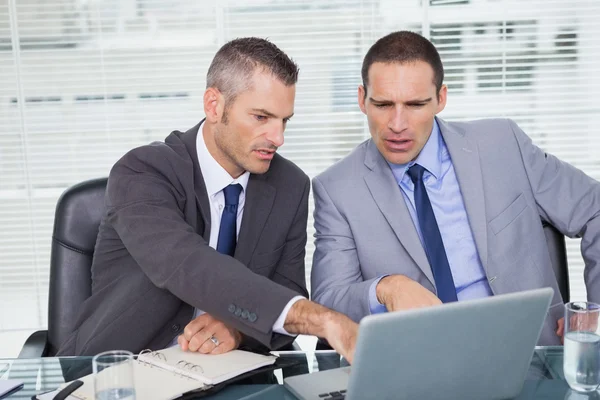 Des hommes d'affaires sérieux travaillant sur leur ordinateur portable — Photo