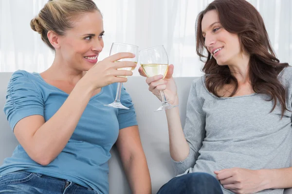 快乐的女人坐在沙发上同时叮当响其葡萄酒杯 — 图库照片
