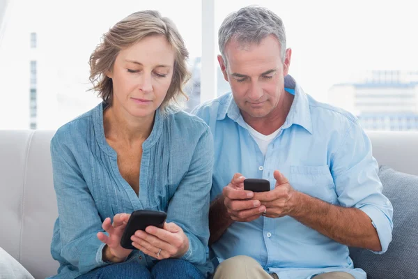 Lachende paar met behulp van hun smartphones — Stockfoto