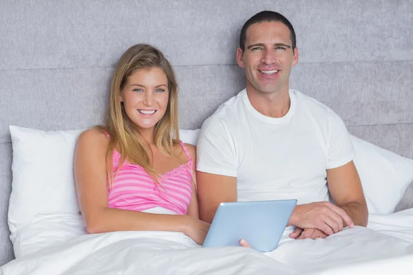 Happy young couple using their tablet pc together in bed — Stock Photo, Image