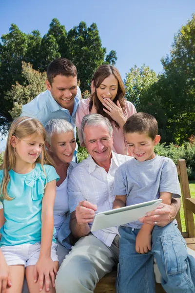 Familia multi generación con una tableta PC sentado en el parque — Foto de Stock