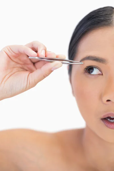 Half face of apprehensive natural woman using tweezers — Stock Photo, Image