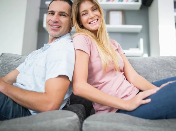 Conteúdo casal sentado de volta para trás no sofá juntos — Fotografia de Stock