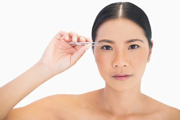 Serious natural model using tweezers for her eyebrow — Stock Photo, Image