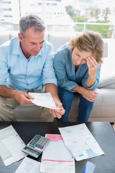 Couple sitting on their couch paying their bills — Stock Photo, Image