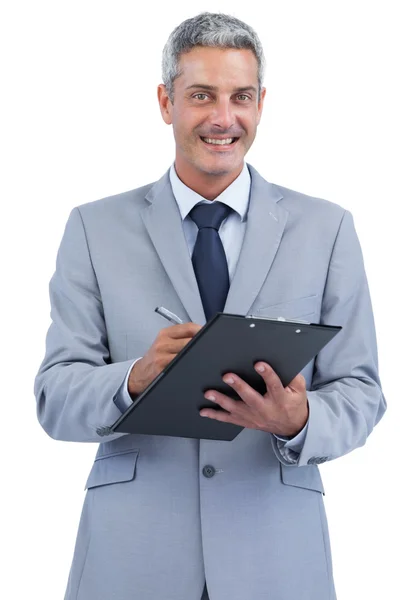 Hombre de negocios alegre sujetando el portapapeles y tomando notas — Foto de Stock