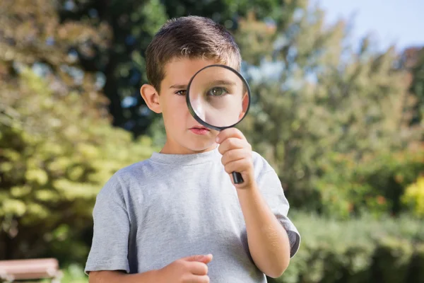 Cute boy looking through a magnifying glass — Stock Photo, Image