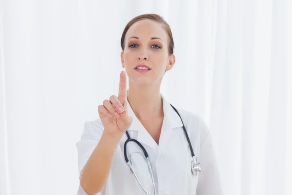 Концентрована медсестра позує, вказуючи на щось — стокове фото